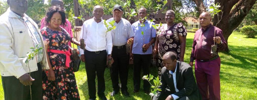 CHAIRPERSON LC V  "SQUATTING" WHILE  RECEIVING ORANGE SEEDLINGS FROM OWC